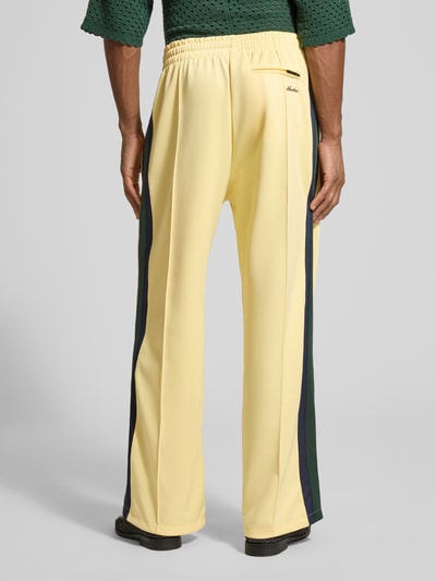 Männermodel trägt Trackpants mit Galonstreifen von ANOTHER COTTON LAB in Gelb mit seitlichen Streifen, Relaxed Fit, Ganzkörperansicht Rückansicht.