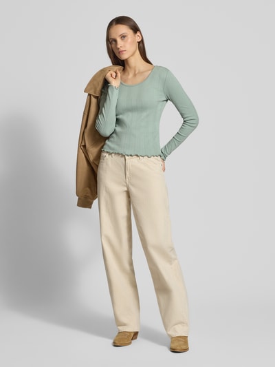 Frauenmodel trägt Slim Fit Langarmshirt aus Bio-Baumwoll-Mix Modell 'TENNA LIFE' von ONLY, Optik: Unifarben, feines Lochstrickmuster, U-Boot-Ausschnitt, Ärmelform: Langarm, Ärmelabschluss: Frill, Rumpfabschluss: Frill, Materialverarbeitung: Feinstrick, Ganzkörperansicht von vorne.