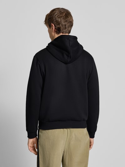 Männermodel trägt Hoodie mit Kapuze Modell 'BRADLEY' von Jack & Jones in Schwarz, Material-Mix, lockerer Schnitt, Ganzkörperansicht Rückansicht.