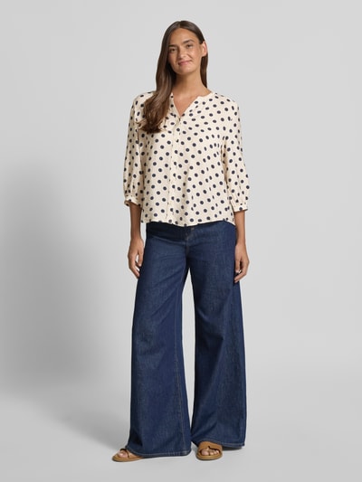 Vrouwenmodel draagt Regular Fit Bluse aus Viskose-Mix Modell 'Alma' van FREE/QUENT met V-hals en 3/4-mouw, crème met zwarte stippen, context: damesblouse, ruglengte 60 cm, mouwlengte 43 cm, geheelaanzicht van voren