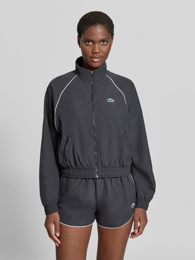 Frauenmodel trägt Relaxed Fit Trainingsjacke mit Logo-Patch von Lacoste in Dunkelgrau mit weißen Kanten, Damen Trainingsjacke von Lacoste Sport, Nahaufnahme Oberkörper.