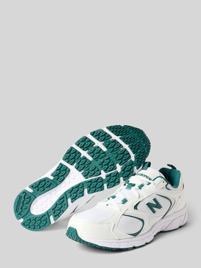 Produktfoto, Sneaker mit Kontrastbesatz von New Balance, weiße Oberfläche mit grünen Details, strukturierte grüne Sohle, runde Form, Schnürverschluss, Label-Detail, abgerundete Form, strukturierte Sohle, Absatzhöhe 3 cm, Schafthöhe 8 cm, Schaftweite 9 cm.
