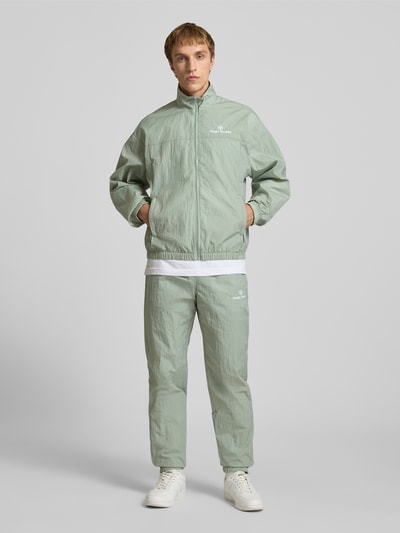 Männermodel trägt Regular Fit Jacke mit Stehkragen Modell 'Nayla' von SERGIO TACCHINI in hellem Grün, mit Reißverschluss, Eingrifftaschen, elastische Abschlüsse, Rückenlänge 69 cm, Ärmellänge 61 cm, Ganzkörperansicht von vorne.