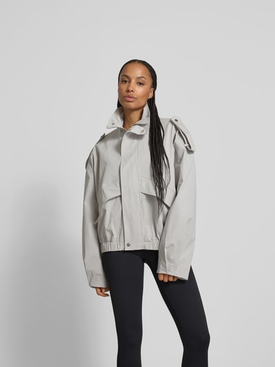 Frauenmodel trägt Jacke mit Stehkragen von black palms aus Baumwolle-Elasthan-Mix, Relaxed-Fit, seitliche Eingrifftaschen, durchgehender Reißverschluss, Rückenlänge 60 cm, Brustweite 70 cm, Ärmellänge 69 cm, helle Farbe, glatte Oberfläche, Ganzkörperansicht von vorne.