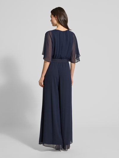 Frauenmodel trägt Jumpsuit aus fließendem Stoff mit Bindegürtel von Vera Mont in Dunkelblau, Chiffon, weites Bein, Ganzkörperansicht Rückansicht. Rückenlänge bei Größe 36: 146 cm, Brustweite: 33 cm, Ärmellänge: 30 cm, Gesamtlänge: 147 cm, Innenbeinlänge: 81 cm.