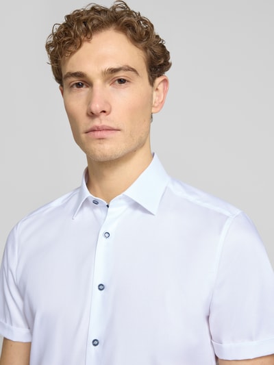 Männermodel trägt Slim Fit Business-Hemd mit Kentkragen von OLYMP Level Five, weiß, glatte Textur, Nahaufnahme Oberkörper, Baumwoll-Elasthan-Mix.