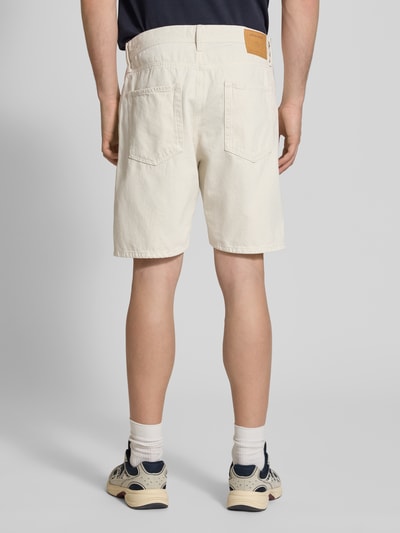 Männermodel trägt Loose Fit Jeansshorts mit Eingrifftaschen Modell 'TONY' von Jack & Jones in Off-White, Used-Look, Ganzkörperansicht Rückansicht.