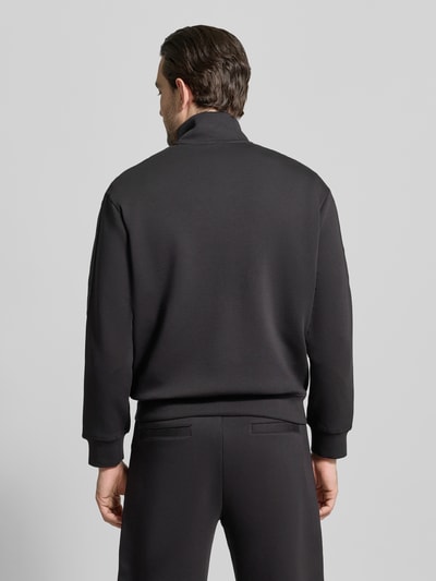 Männermodel trägt Sweatjacke mit Stehkragen und Zweiwege-Reißverschluss von Emporio Armani, Baumwoll-Mix mit Stretch-Anteil, Regular-Fit, schwarze Farbe, glatte Oberfläche, Eingrifftaschen, Rückenlänge 66 cm, Ärmellänge 62 cm, Ganzkörperansicht Rückansicht.