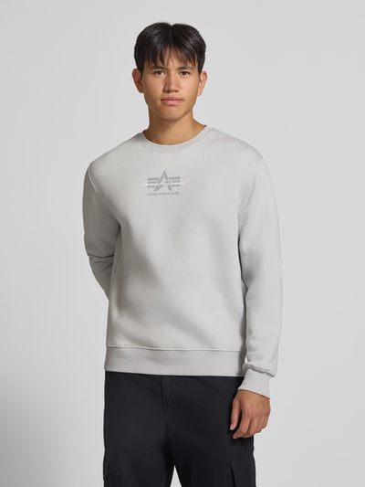 Männermodel trägt Regular Fit Sweatshirt aus Baumwoll-Mix mit Label-Detail von Alpha Industries in Hellgrau, Ganzkörperansicht von vorne. Rückenlänge bei Größe M: 66 cm, elastische Abschlüsse.