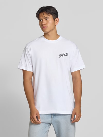 Männermodel trägt Regular Fit T-Shirt aus reiner Baumwolle Modell 'Pup' von Carhartt Work In Progress in Weiß, Ganzkörperansicht von vorne. Herren T-Shirt von Carhartt Work In Progress, Regular Fit, Label-Print, Rückenlänge bei Größe M: 77 cm.