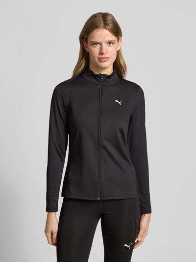 Kobiece model nosi Jacke mit Stehkragen od PUMA w kolorze czarnym, slim fit, materiał z dodatkiem stretchu, widok całej sylwetki z przodu.