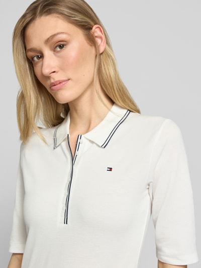 Frauenmodel trägt Slim Fit Poloshirt aus Lyocell-Mix von Tommy Hilfiger, Optik: Unifarben, Logo-Stitching, Kontraststreifen, Knopfleiste, 1/2-Arm, Materialverarbeitung: Piqué, Nahaufnahme Oberkörper.