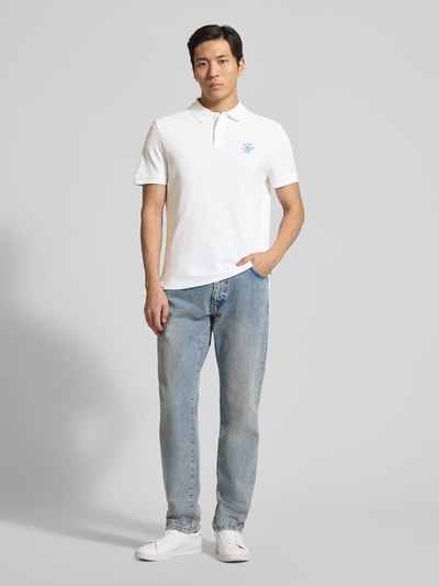 Männermodel trägt Regular Fit Poloshirt aus reiner Baumwolle von Tommy Hilfiger, unifarben in Weiß, Piqué-Struktur, Logo-Stitching, Ganzkörperansicht von vorne.