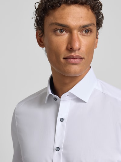 Mannelijk model draagt Slim Fit Businesshemd in Premiumkwaliteit van OLYMP, effen katoenmix, Kentkraag, contrastknopen, popeline. Nahaufnahme Oberkörper.