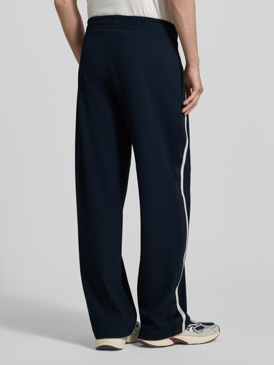 Männermodel trägt trainingsbroek uit mix van viscose en elastaan, steekzakken, galonstrepen, labelprint, recht pasvorm, EA7 Emporio Armani. Ganzkörperansicht Rückansicht.