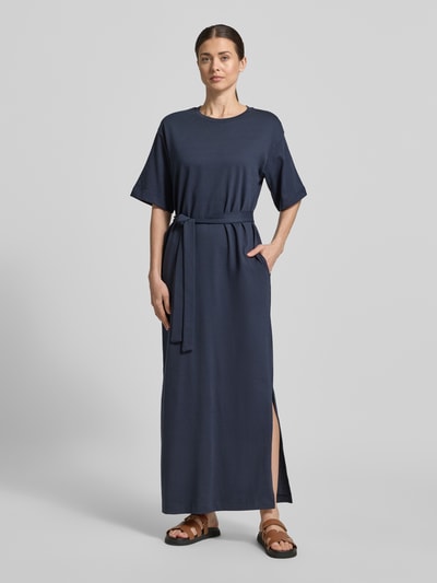 Vrouwenmodel draagt Loose Fit Maxikleid aus reiner Baumwolle Modell 'ESSENTIAL' van Selected Femme, unikleuren, maxi lengte, ronde hals, korte mouw, bindriem in de taille, rechte zoom met zijsplitten, steekzakken, katoen, volledige lichaamsaanzicht van voren.