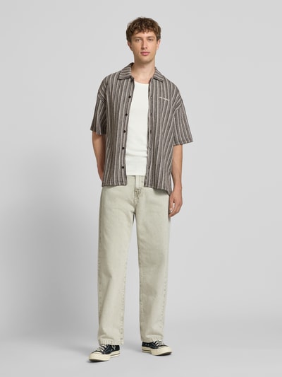 Männermodel trägt Relaxed-Fit Freizeithemd mit Label-Stitching Modell 'Forno' von Pegador aus Reine Baumwolle im Allover-Look, Kentkragen und Knopfleiste, Ganzkörperansicht von vorne. Kontext: Rückenlänge bei Größe M 74 cm, Schulterbreite 40 cm, Ärmellänge 35 cm.