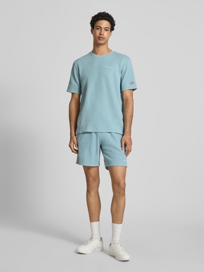 Männermodel trägt T-Shirt mit Strukturmuster und Label-Stitchings von CHAMPION, hellblauer Farbton, Baumwoll-Mix, Regular Fit, Ganzkörperansicht von vorne