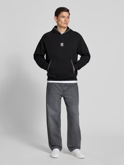 Männermodel trägt Regular Fit Hoodie aus reiner Baumwolle Modell 'DAROHOOD' von HUGO, unifarben, Kängurutasche, Ganzkörperansicht von vorne.