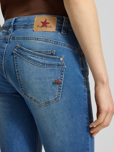 Kobieta nosi jeansy o dł. 7/8 model 'Malibu' od Buena Vista, mieszanka bawełny z dodatkiem streczu, krój slim fit, ujęcie z tyłu zbliżenie. Szerokość w rozmiarze S: 38 cm, długość wewnętrzna nogawki w rozmiarze S: 68 cm.