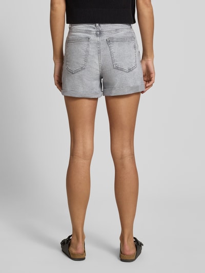 Männermodel trägt szare szorty jeansowe z wysokim stanem High Waist Jeansshorts mit Umschlag Modell 'MONI' von Noisy May, mieszanka bawełny i elastanu, wpuszczane kieszenie, brzeg, szerokość w rozmiarze S: 35 cm, długość wewnętrzna nogawki w rozmiarze S: 9 cm, widok całej sylwetki z tyłu