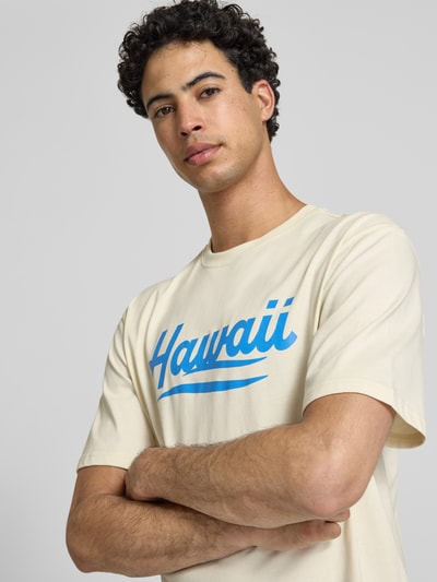 Männermodel trägt Herren T-Shirt von Only & Sons, Modell 'Relaxed Fit T-Shirt aus reiner Baumwolle Modell 'RICO'' mit Optik: Unifarben, Motiv-Print, Passform: Relaxed-Fit, Rundhals-Ausschnitt, Ärmelform: Kurzarm, Materialverarbeitung: Jersey, Material: Reine Baumwolle, helle Farbgebung, blaues Motiv-Print, glatte Textur, Nahaufnahme Oberkörper.