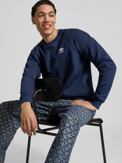 Männermodel trägt Regular Fit Sweatjacke aus Baumwoll-Mix von adidas Originals in Unifarben mit Logo-Stitching, Nahaufnahme Oberkörper.