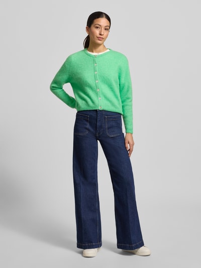 Vrouwenmodel draagt Strickjacke mit Knopfleiste Modell 'VITOW' van American Vintage in lichtgroen, mix van alpaca en lamswol, geribde boorden, ronde hals, losse pasvorm, knopenrij, casual stijl, volledige lichaamsvoorzijde.