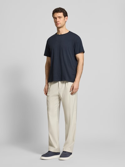 Männermodel trägt Regular Fit T-Shirt aus reiner Baumwolle Modell 'HASPEN' von SELECTED HOMME in Melange-Optik mit Rundhalsausschnitt, kurzarm, kombiniert zu heller Hose, Farbkontrast zwischen Dunkelblau und Beige, Ganzkörperansicht von vorne.