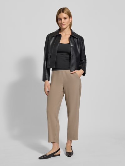 Frauenmodel trägt Stoffhose in verkürzter Passform Modell 'ELENA' von Cambio im Material-Mix mit elastischem Logo-Bund und Eingrifftaschen, lockerer Schnitt, beige, Ganzkörperansicht von vorne.