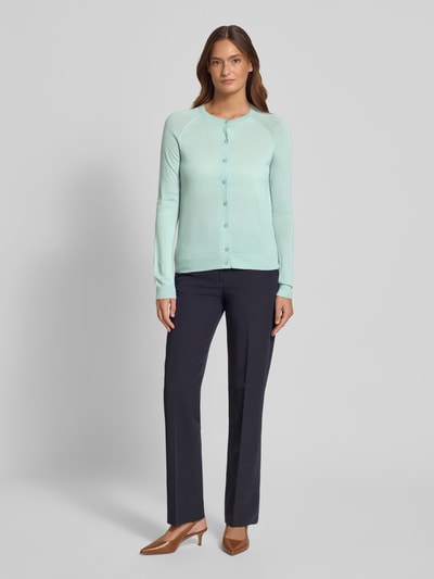Modelka nosi Regular Fit Strickjacke aus reiner Schurwolle Modell 'FONAMI' von BOSS, jednokolorowy, drobny splot, okrągły dekolt, długie raglanowe rękawy, listwa guzikowa, zakończenia prążkowane, czysta żywa wełna, krój regular fit, pełny widok z przodu.