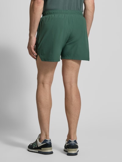 Männermodel trägt Shorts mit elastischem Bund von HALO in Dunkelgrün, Material-Mix mit Stretch-Anteil, Label-Print, Regular-Fit, Ganzkörperansicht Rückansicht.
