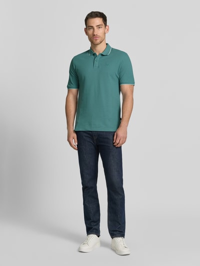 Mężczyzna nosi Slim Fit Poloshirt mit Stitching von Jack & Jones Premium, bawełna, krój slim fit, zapięcie na guziki, zielony, widok całej sylwetki z przodu.