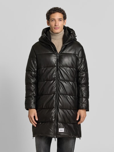 Männermodel trägt Regular Fit Mantel in Stepp-Optik Modell 'EMMET' von khujo in Schwarz, glatte Textur, Ganzkörperansicht von vorne.
