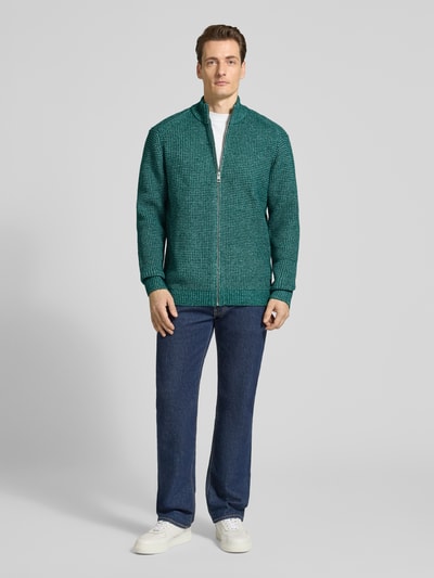 Männermodel trägt Regular Fit Strickjacke mit Woll-Anteil von Tom Tailor, grüne Melange-Optik, Reißverschluss, Stehkragen, Ganzkörperansicht von vorne.