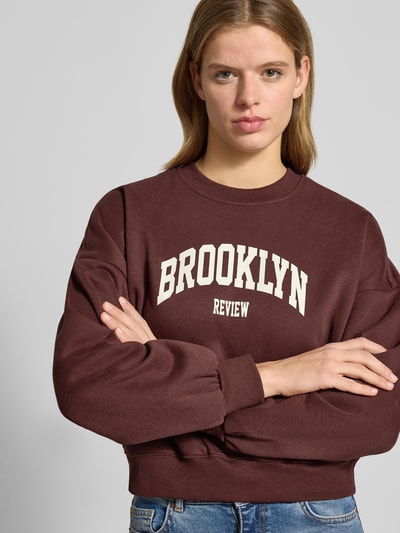 Frauenmodel trägt Sweatshirt mit Label-Print und Rundhalsausschnitt von Review, Baumwoll-Mix, Relaxed-Fit, Nahaufnahme Oberkörper.