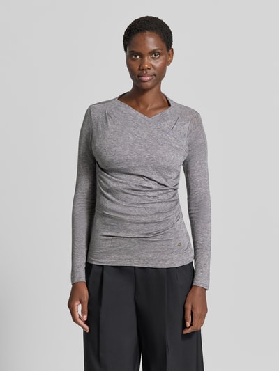 Frauenmodel trägt Longsleeve in Wickel-Optik von windsor., melierter Grauton, taillierter Schnitt, Label-Applikation, Ganzkörperansicht von vorne. Elastischer Lyocell-Woll-Mix, Rückenlänge bei Größe 36 beträgt 58 cm.