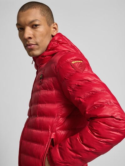 Männermodel trägt rote Steppjacke mit Zweiwege-Reißverschluss Modell 'Charles' von Blauer Usa, Regular Fit, Label-Detail, Nahaufnahme Oberkörper.