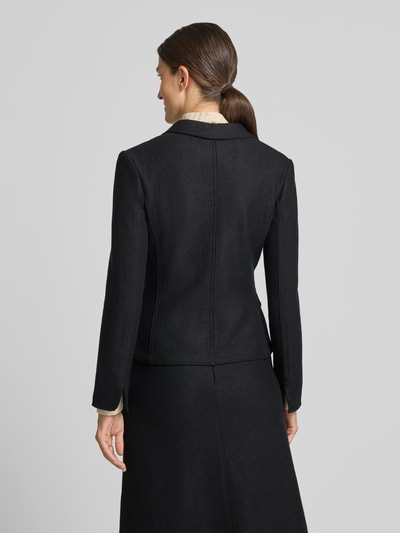 Frauenmodel trägt Slim Fit Kurzblazer aus reiner Schurwolle von Marc Cain in Schwarz mit Reverskragen, Pattentaschen, Rückansicht, Ganzkörperansicht.