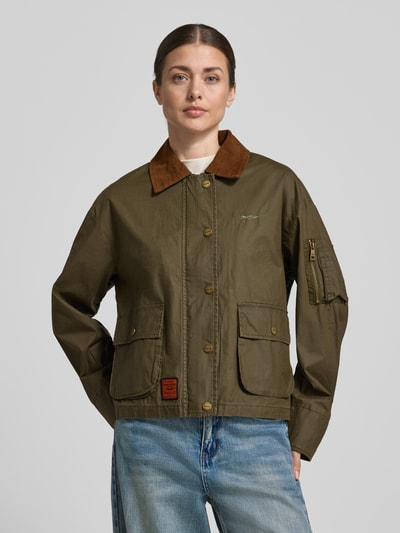 Frauenmodel trägt Jacke aus Baumwolle mit Pattentaschen von Original Bombers in Oliv, Regular-Fit, Umlegekragen, Knopfleiste, Reine Baumwolle, Ganzkörperansicht von vorne. Rückenlänge 60 cm, Schulterbreite 52 cm, Brustweite 58 cm, Ärmellänge 57 cm.