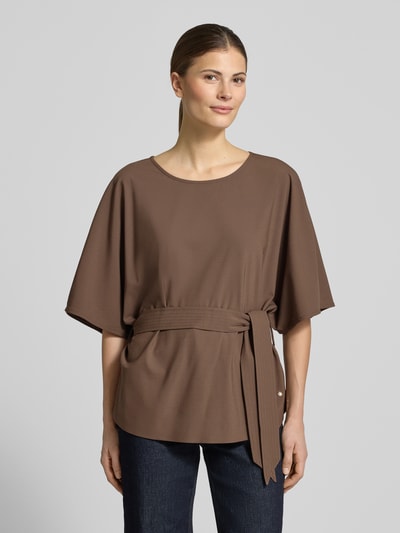 Vrouwenmodel draagt Relaxed Fit blouse uit viscosemix model 'Rikas' van MOS MOSH, met stoffen band, halflange mouwen, ronde hals, kleur bruin, vooraanzicht bovenlichaam, ruglengte maat S 63 cm, mouwlengte maat S 28 cm.