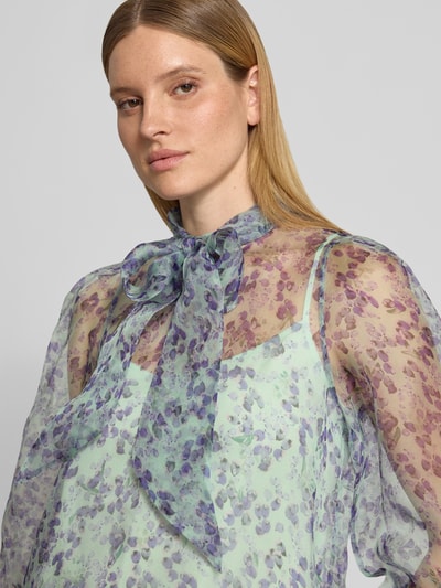 Vrouwenmodel draagt Regular Fit strikblouse uit zuiver zijde met all-over look, semi-transparant van Marc Cain, nahaufnahme bovenlichaam.