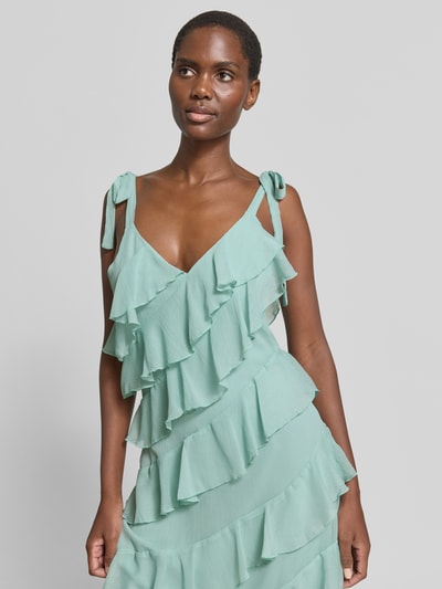 Vrouwenmodel draagt mintgroene midi-jurk met volants, model 'LUNA' van Vila in a-lijn met bandjes en vetersluiting, nahaufnahme bovenlichaam.