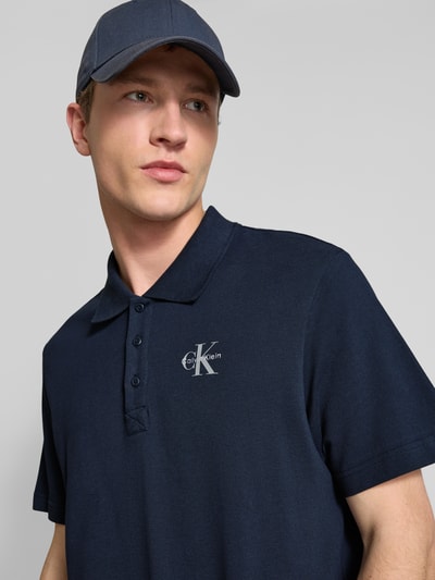 Männermodel trägt Easy Fit Poloshirt mit Polokragen von Calvin Klein Jeans, Reine Baumwolle, Label-Stitching, Nahaufnahme Oberkörper.