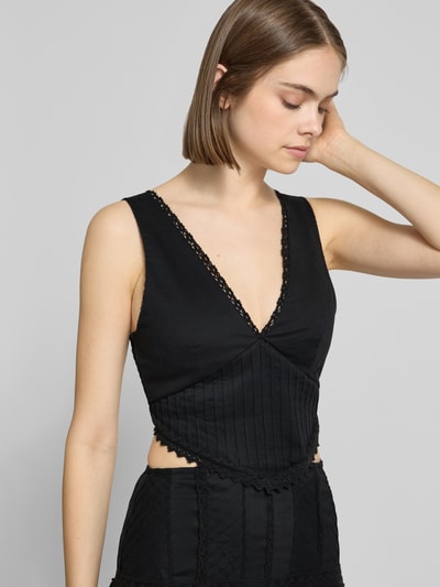 Frauenmodel trägt Maxikleid mit rückseitigem Cut Out Modell 'ALINA' von Topshop aus schwarzem Baumwoll-Mix mit Stretch-Anteil, taillierter Schnitt, V-Ausschnitt, Häkelspitze und Smok-Details, Nahaufnahme Oberkörper.