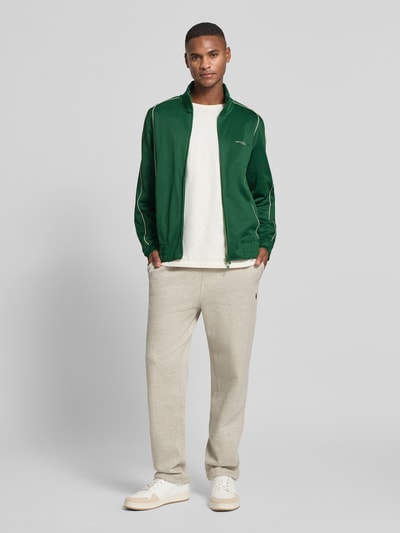 Männermodel trägt grüne Sweatjacke mit Reißverschluss Modell 'FELPA' von Armani Exchange aus Baumwoll-Mix, Regular-Fit, Ganzkörperansicht von vorne.