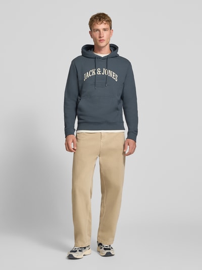 Männermodel trägt Regular Fit Hoodie aus Baumwoll-Mix Modell 'Denver' von JACK & JONES in Dunkelblau, Känguru-Tasche, Ganzkörperansicht von vorne.