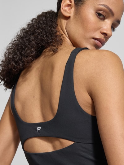 Frauenmodel trägt Slim Fit Top mit integriertem BH Modell 'Pureluxe' von Fabletics, schwarze Farbe, Rückenlänge 30 cm, Nahaufnahme Rückansicht.