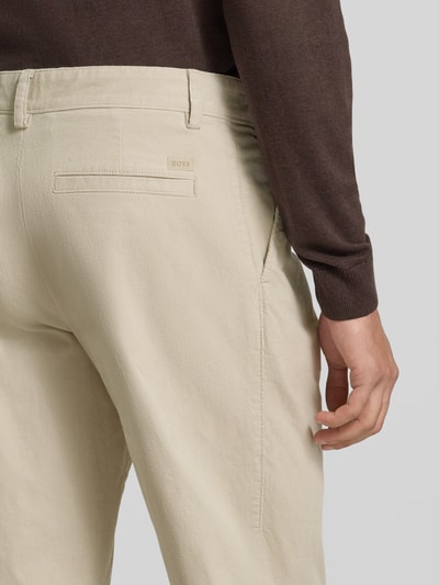 Männermodel trägt Regular Fit Cordhose aus Baumwoll-Mix Modell 'Pleated 3' von BOSS Orange in Beige, Detailaufnahme Rückansicht.