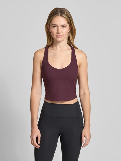 Frauenmodel trägt Cropped Top mit integriertem Bustier Modell 'Anywhere' von Fabletics aus Elastischer-Material-Mix, Farbe Bordeaux, ganzkörperansicht von vorne. Rückenlänge bei Größe S: 42 cm.
